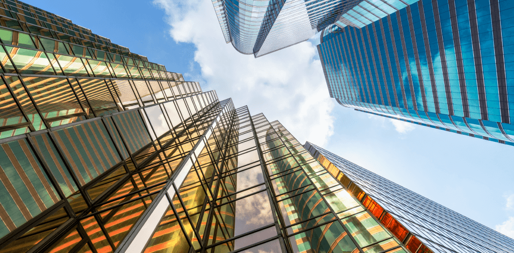 Upward shot of towering glass skyscrapers against a cloudy blue sky