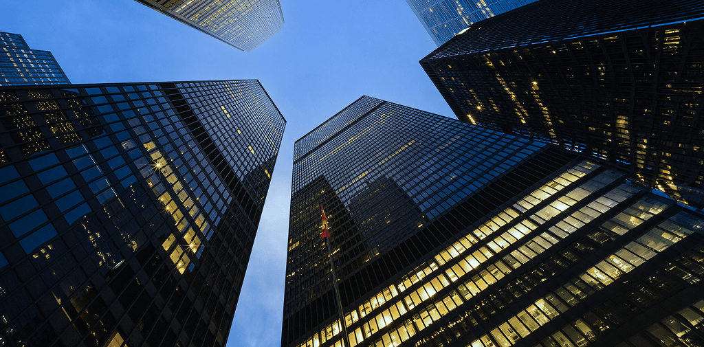 Dark skyscrapers viewed from below, illuminated by golden lights